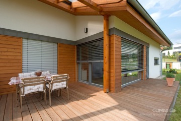 zatažené i napůl zatažené stříbrné venkovní žaluzie u částečně dřevěného domu